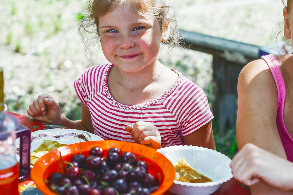 Criança à mesa diante de uma tigela de frutas